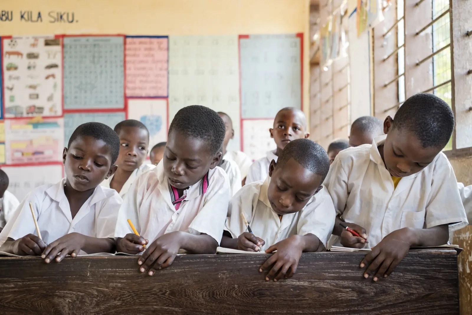 Primary school pupils writing together in a classroom in Masasi, Tanzania