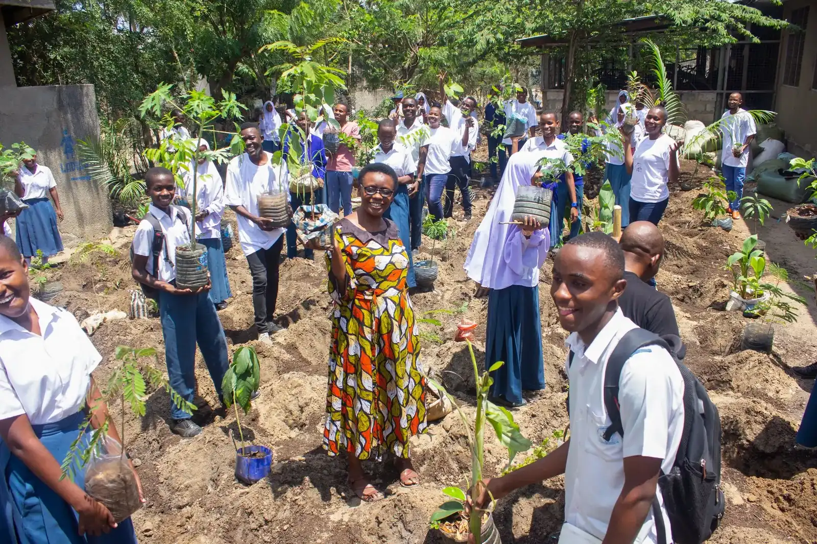 Students, teachers, and parents planting a micro-forest at a school in Dar es Salaam