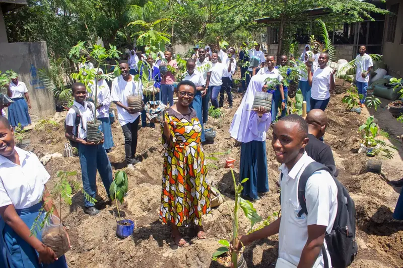 Students, teachers, and parents planting trees at a school in Dar es Salaam